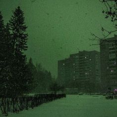 the snow is falling in front of some tall buildings on a snowy day at night