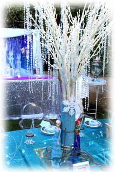 there is a vase with white branches in it on the blue table cloth and silverware