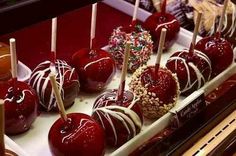 chocolate covered apples are lined up on a display tray with candy sticks sticking out of them