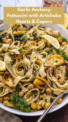 garlic and artichoke pasta in a white bowl with lemon wedges