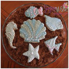 decorated cookies in the shape of seashells and starfish on a glass plate