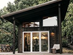 a small wooden cabin with glass doors and windows