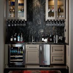 a home bar with wine glasses and liquor bottles on the shelves, along with an area rug