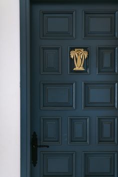 a black door with a gold palm tree on the front and side paneled doors