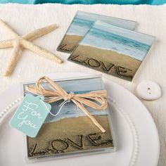 two coasters on a plate with the word love written in sand and starfish