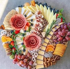 a platter filled with lots of different types of cheese and meats on top of each other