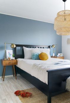 a bedroom with blue walls, white bedding and wooden flooring is pictured in this image