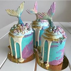 there are two cakes decorated with mermaid tail decorations on top of each other, one is blue and the other is pink