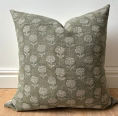 a green pillow sitting on top of a hard wood floor next to a white wall