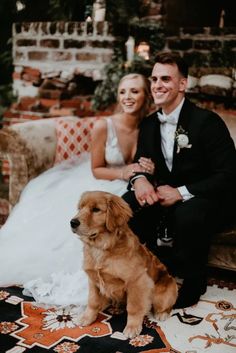 a bride and groom sitting on a couch with their dog in front of the camera