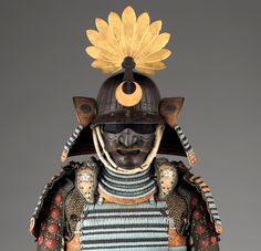 an elaborately decorated japanese armor with gold accents and feathers on it's head