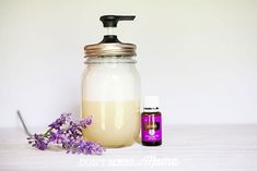 a bottle of liquid next to a lavender flower