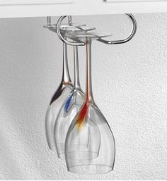 two wine glasses hanging from a hook on a wall in a room with white walls