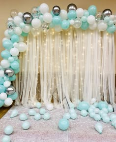 the balloon arch is decorated with blue and white balloons, streamers, and sheer curtains