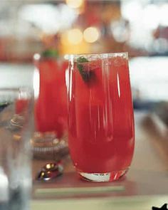 two glasses filled with red liquid sitting on top of a table next to each other