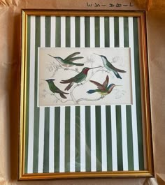 three birds are sitting on a branch in a gold frame with green and white stripes