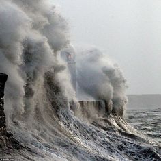 a lighthouse surrounded by huge waves in the ocean