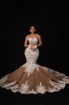 a woman in a brown and white gown standing on a black background with her hands behind her back