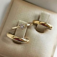 two gold wedding rings with a diamond on each one in front of a white box