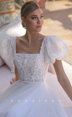 a woman in a white wedding dress sitting on a couch with her hands behind her back