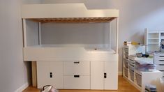 there is a bunk bed in the corner of this room with white furniture and drawers