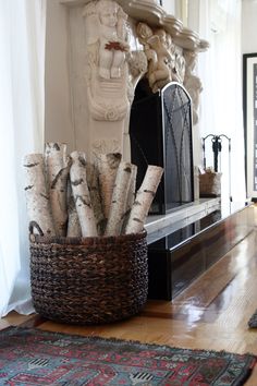 a basket filled with logs sitting on top of a wooden floor next to a fireplace