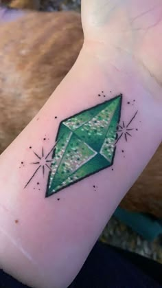 a small green diamond tattoo on the wrist