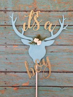 a cake topper with the words it's a boy and a deer head