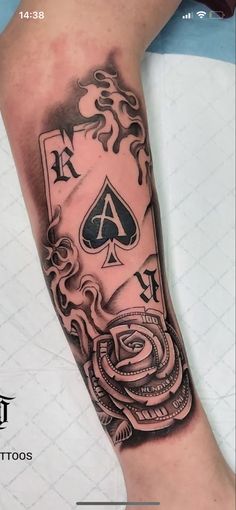 a black and grey tattoo on the arm of a person with a card in it