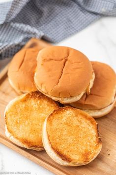 three hamburgers sitting on top of a wooden cutting board