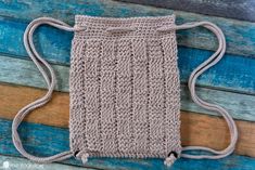 a crocheted bag sitting on top of a wooden table next to a blue wall