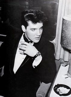 a man in a tuxedo sitting at a table with a plate of food