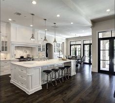 an image of a kitchen with white cabinets and gray countertops in front of glass doors