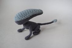 a crocheted toy cat with a hat on its head and tail, standing upright