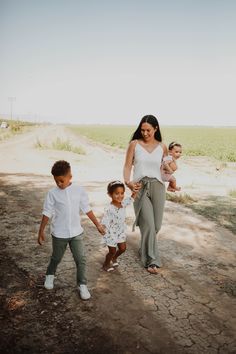 a woman walking with two children down a dirt road