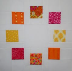 a quilted wall hanging with different colored squares on it's sides and dots in the middle