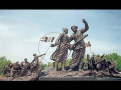 there is a bronze statue with many women holding flags and arrows in front of it