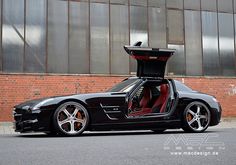 a black sports car parked in front of a brick building with its doors open and the door ajar