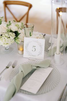 the table is set with white flowers and silverware