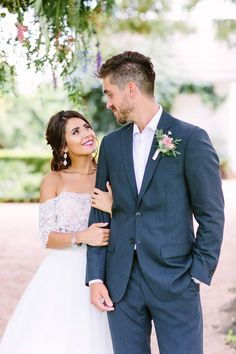 a bride and groom standing under a tree