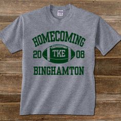 a gray t - shirt with green lettering that reads, home coming to the birmingham football team