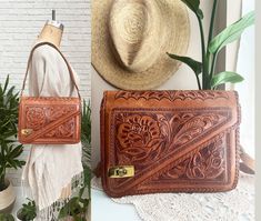 ➳ Beautiful and rare 1960s tooled leather shoulder bag ➳ Crafted from genuine cognac brown leather ➳ Intricate hand-tooled rose design throughout  ➳ Asymmetrical top flap with a brass turn lock closure ➳ Practical interior with multiple compartments, zippered slots, and a license/credit card slot.  ➳ The two-layered leather shoulder strap  ➳ This unique purse is a must-have addition to your vintage collection!  Measurements   ( Taken laying flat )  Length: Width: Depth: Shoulder Strap:   Label & Fabric  100% Genuine Fabric  Made in Monterrey, Mexico Curiosidades Mexicanas De Monterrey  Condition  In great vintage condition overall for it's age, though there are minor flaws along the upper sides of the trim. Some whipstitching has loosened, and there is slight exposure of wiring on one side Hippie Purse, Tooled Leather Bag, Shoulder Bag Vintage, Unique Purses, Tooled Leather, Bag Vintage, Rose Design, Leather Tooling, Handmade Bags