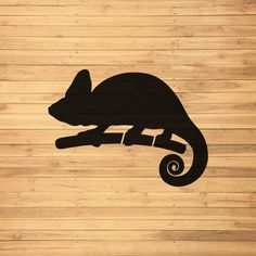 a black silhouette of a chamelon sitting on a wooden surface with its tail curled up