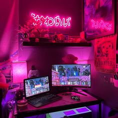 two computer monitors sitting on top of a desk in front of a neon sign that reads wiki