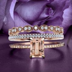 an engagement and wedding ring set in rose gold with diamonds on the band, surrounded by purple roses