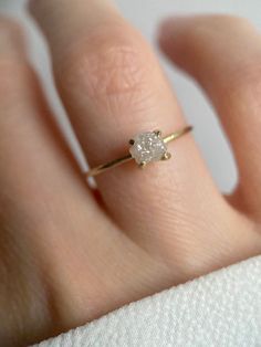 a woman's hand with a diamond ring on top of her finger and the other hand holding it