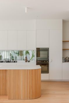 a large kitchen with white cabinets and wooden counter tops, along with an island in the middle