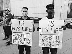 two men holding signs that read is his life, worth less than mine?