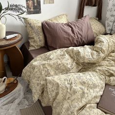 an unmade bed with pillows and blankets on it in a bedroom next to a table