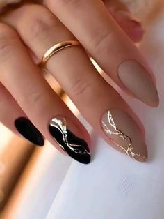 a woman's hand with black and gold nail polishes on her nails,